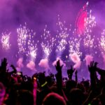 Vibrant EDM concert scene with fireworks, smoke, and enthusiastic crowd enjoying the music.